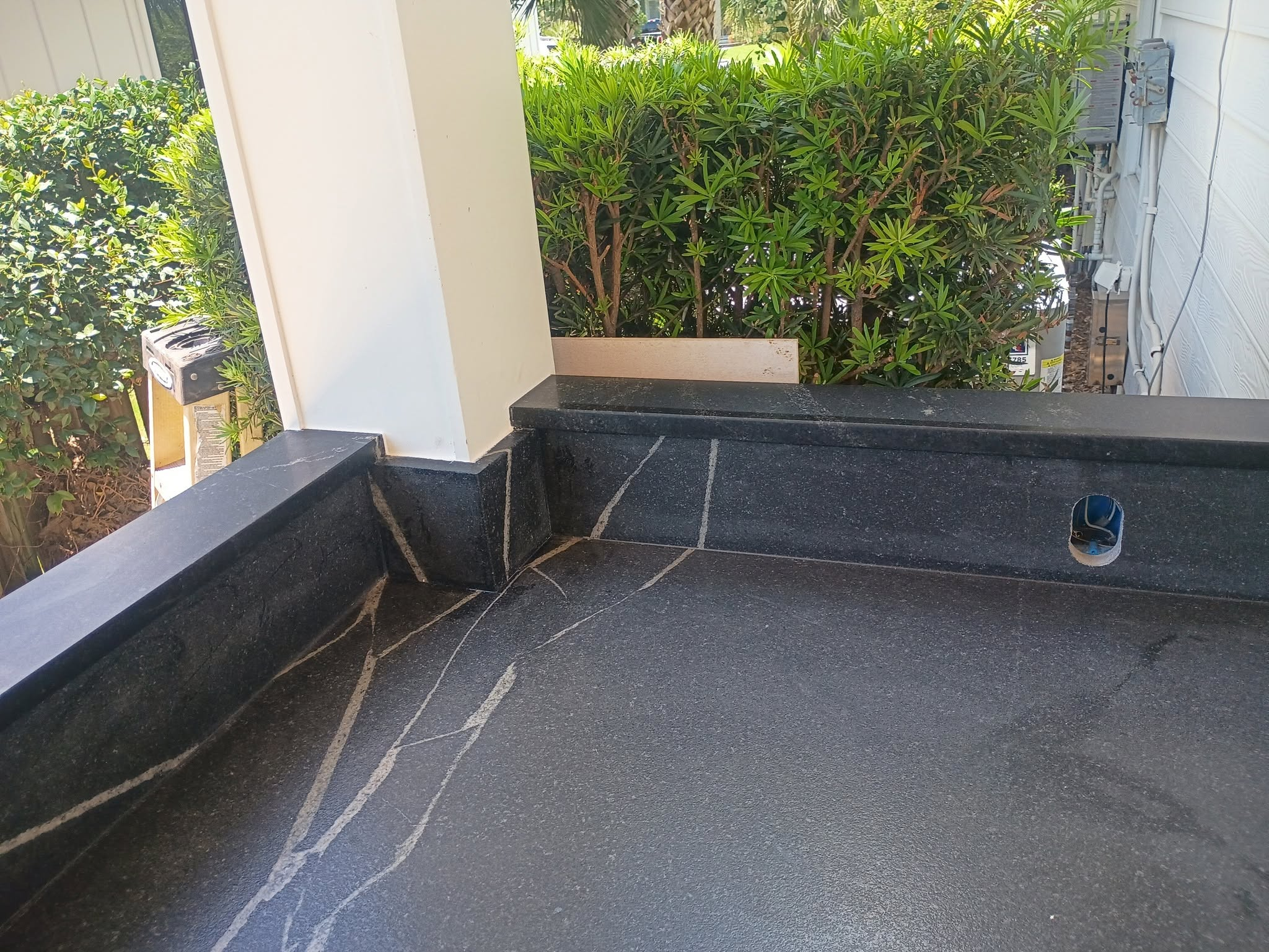 Outdoor kitchen with natural stone countertop and dark cabinets